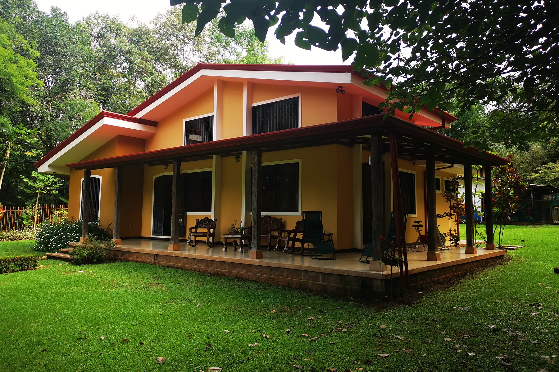 The project's main house with its covered terrace, surrounded by tropical garden